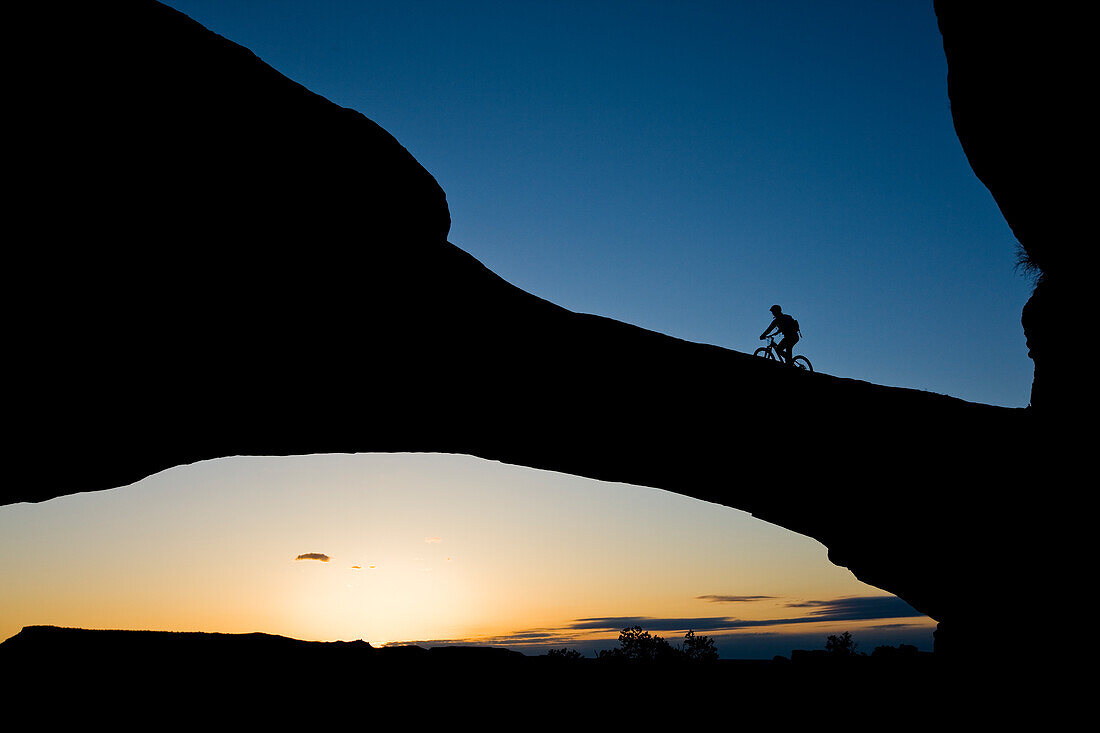 Jess Reilly mountain biking across an arch near Moab, Utah.