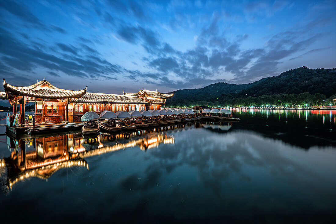 Dramatic sky at West Lake with reflections, pagoda-ship and boats