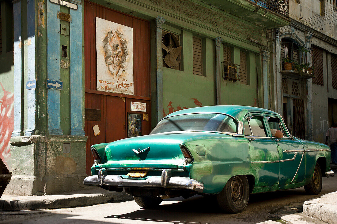 Havana, Cuba - an old car moves down O'Relly through the side streets of Old Havana past an arts organization tucked in an old building