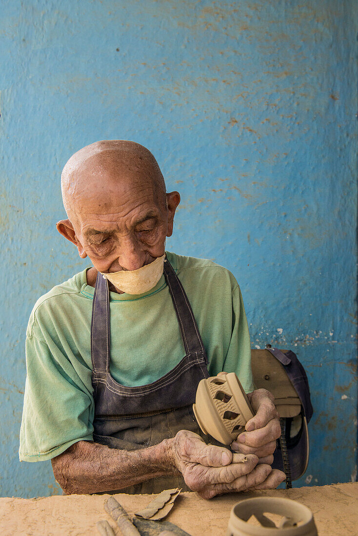 'An unnamed elderly Cuban craftsman carefully sands a candle holder before glazing it at the studio of Daniel Chichi'' Santander, renowned Cuban potter, at the Santander Family Workshop in Trinidad, Sancti Spiritus, Cuba.'''