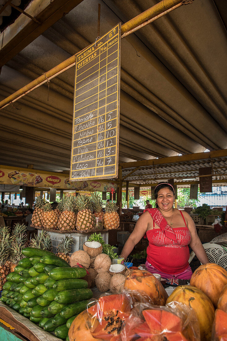 A smiling woman produce vendor stands over her fruits and vegetables at the Agropecuario 19 y B food market in the Vedado section of Havana Cuba.