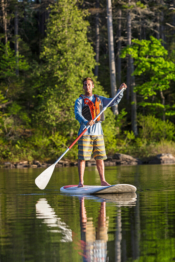 A Man Paddleboarding On Long Pond Near Greenville, Maine