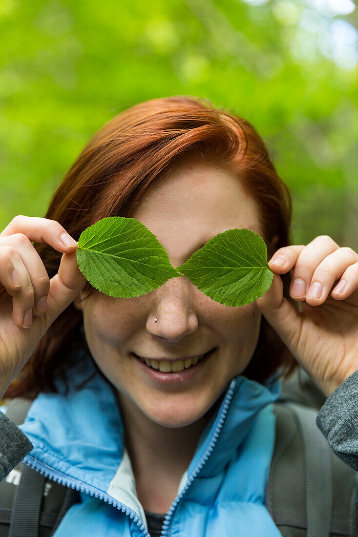 A Young Woman Holds The Beech Leaves In Front Of Her Eyes