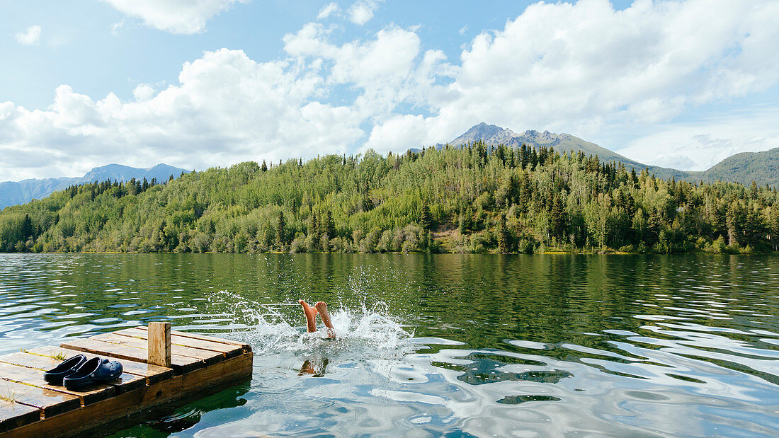 A Person Dives Into Long Lake Along The Mccarthy Road, Alaska, Usa