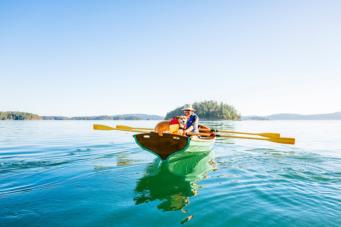 A Man With His Dog In A Rowing Boat In Deer Harbor, Orcas Island, Washington, Usa