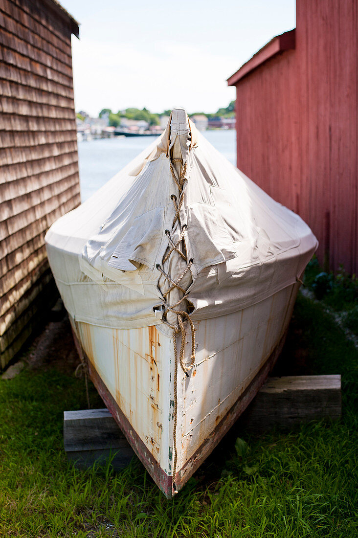 Old boat moored between two barns in summer