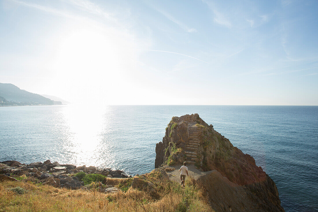 Man walks out to promentory over the sea