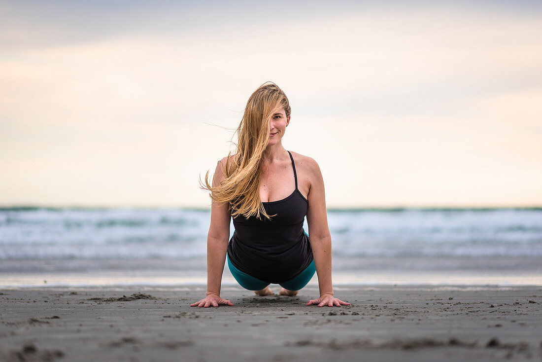 Eine Frau macht Yoga am Strand von Rhode Island an einem windigen und bewölkten Tag