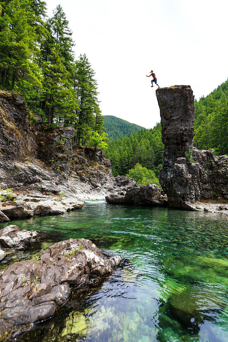 Man Leaping Into A Crystal Clear Pool From Above Rock
