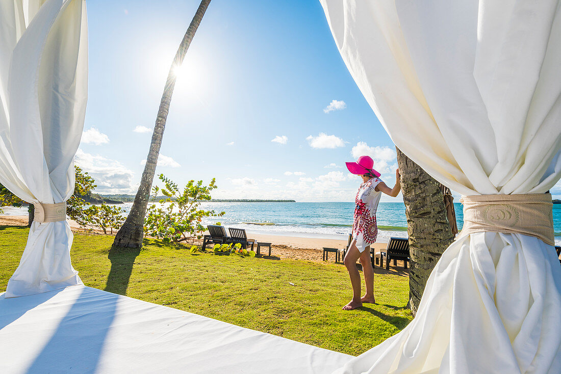 Playa Moron, Las Terrenas, Halbinsel Samaná, Dominikanische Republik, Schöne Frau bewundern die Aussicht von einem Strandbett, MR