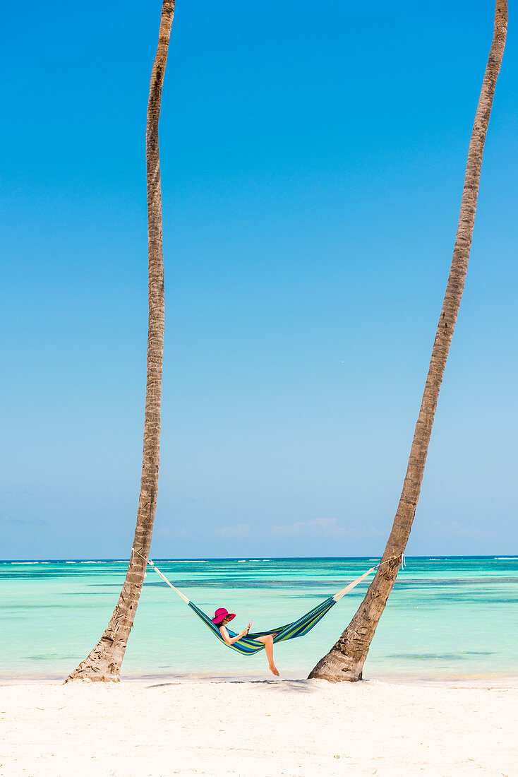 Juanillo Beach, playa Juanillo, Punta Cana, Dominikanische Republik, Frau entspannt auf einer Hängematte auf einem Palmen gesäumten Strand, MR