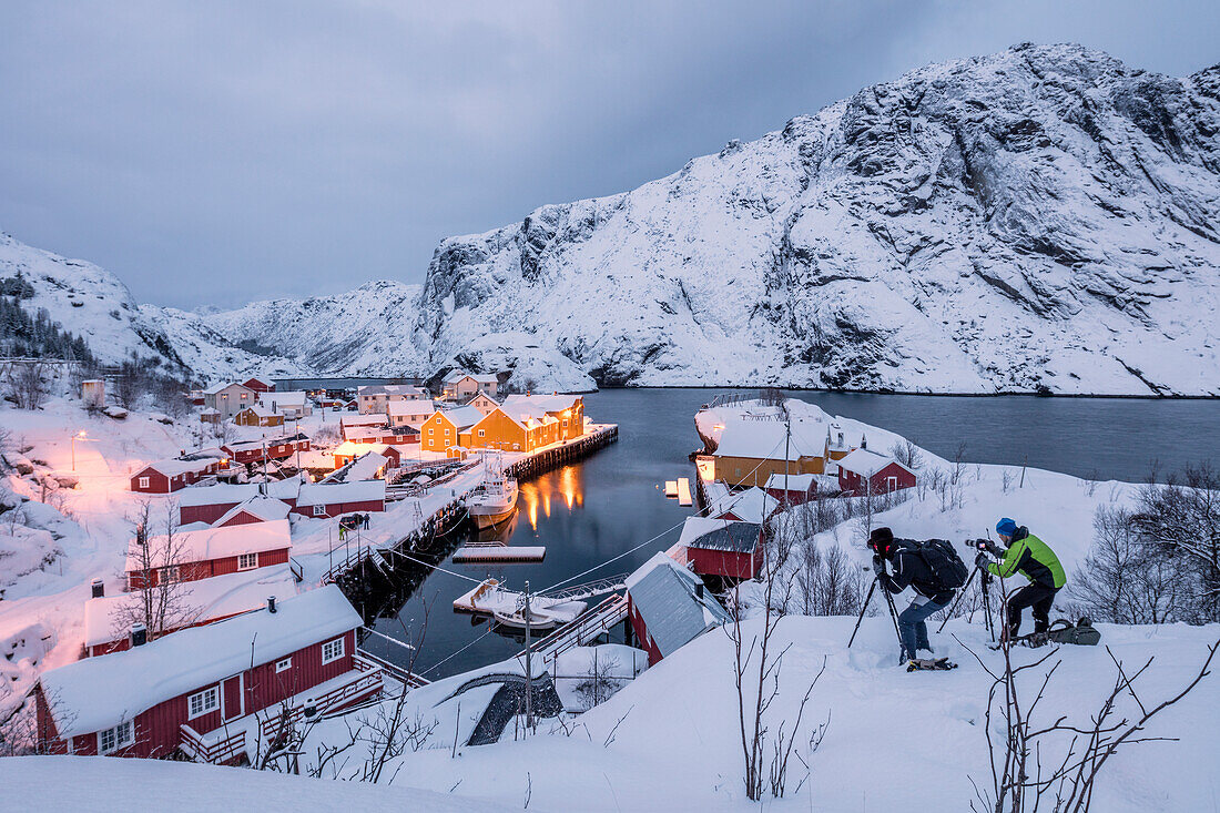 Fotografen in der Dämmerung in der Nähe des Fischerdorfes mit Schnee bedeckt Nusfjord Nordland Lofoten Inseln Nordnorwegen Europa