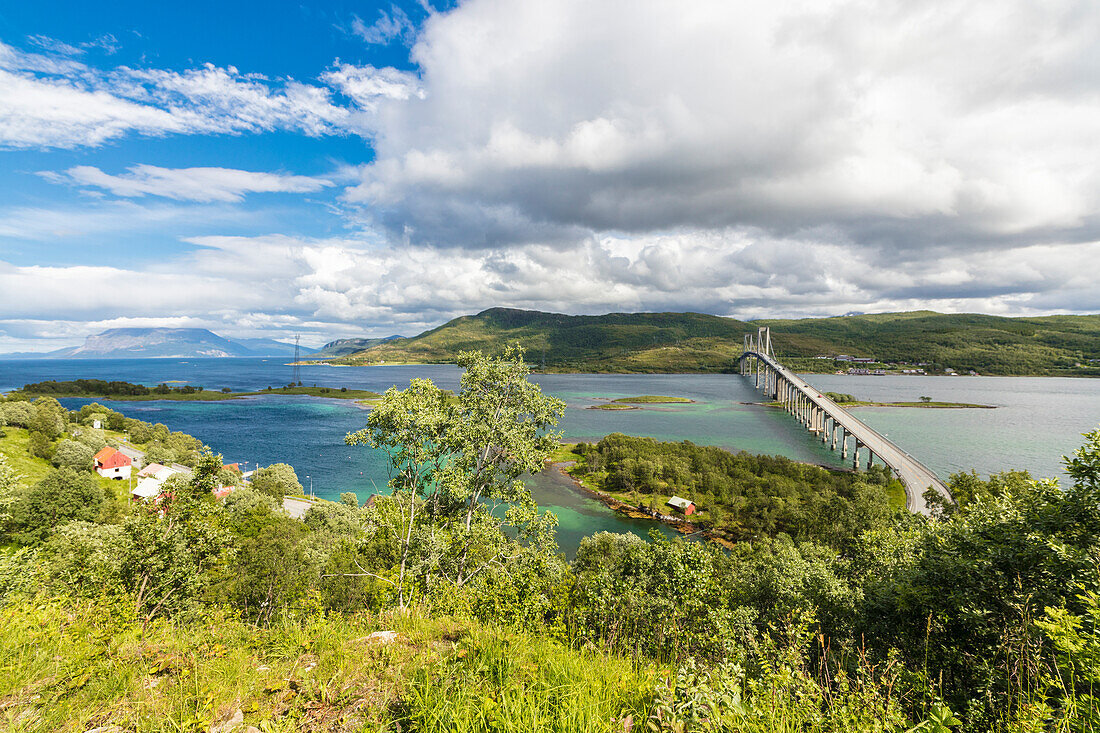 Grüne Wiesen und türkisfarbenes Meer Rahmen der Aufhebung Straße Brücke in Tjeldsundbrua Troms Grafschaft Nordland Norwegen Europa