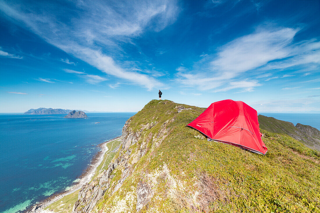 Tent and hiker on mountain ridge overlooking the sea Sorland Vaeroy Island Nordland county Lofoten archipelago Norway Europe