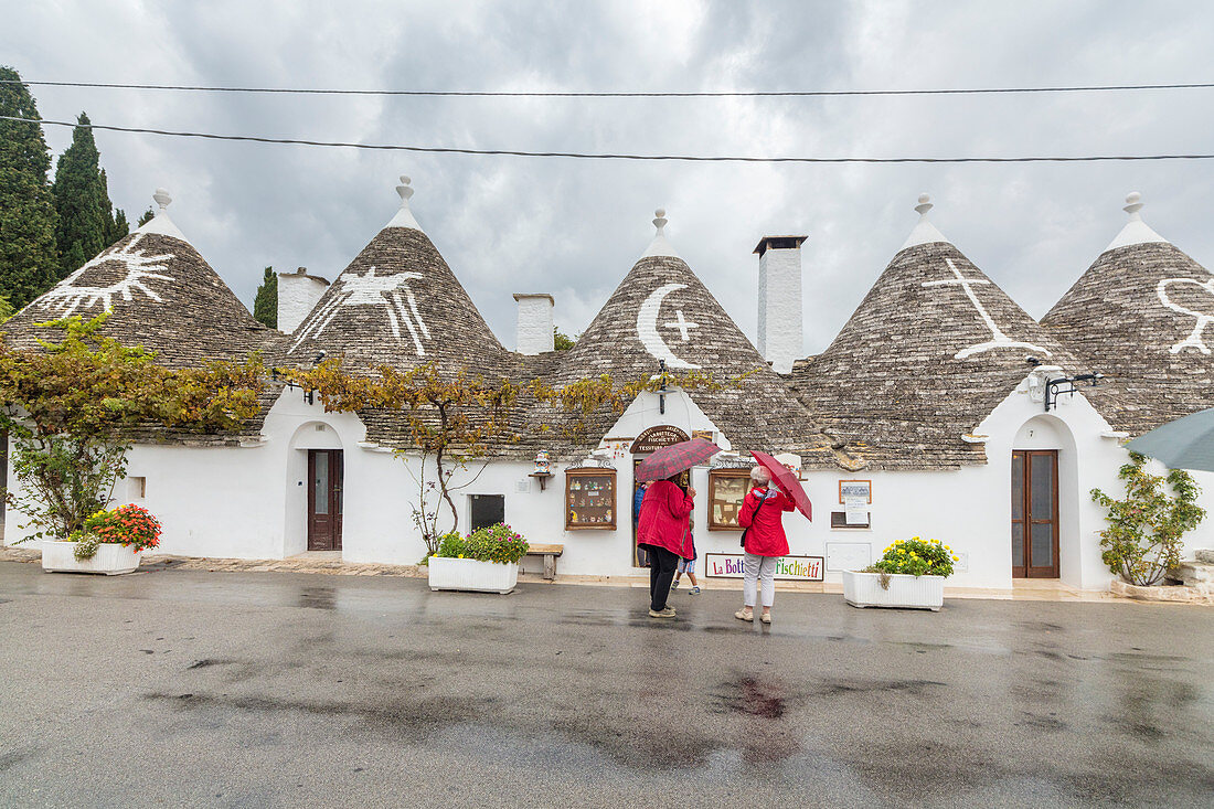 Touristen bewundern die typischen Trulli mit trockenem Stein mit einem konischen Dach Alberobello Provinz Bari Apulien Italien Europa gebaut