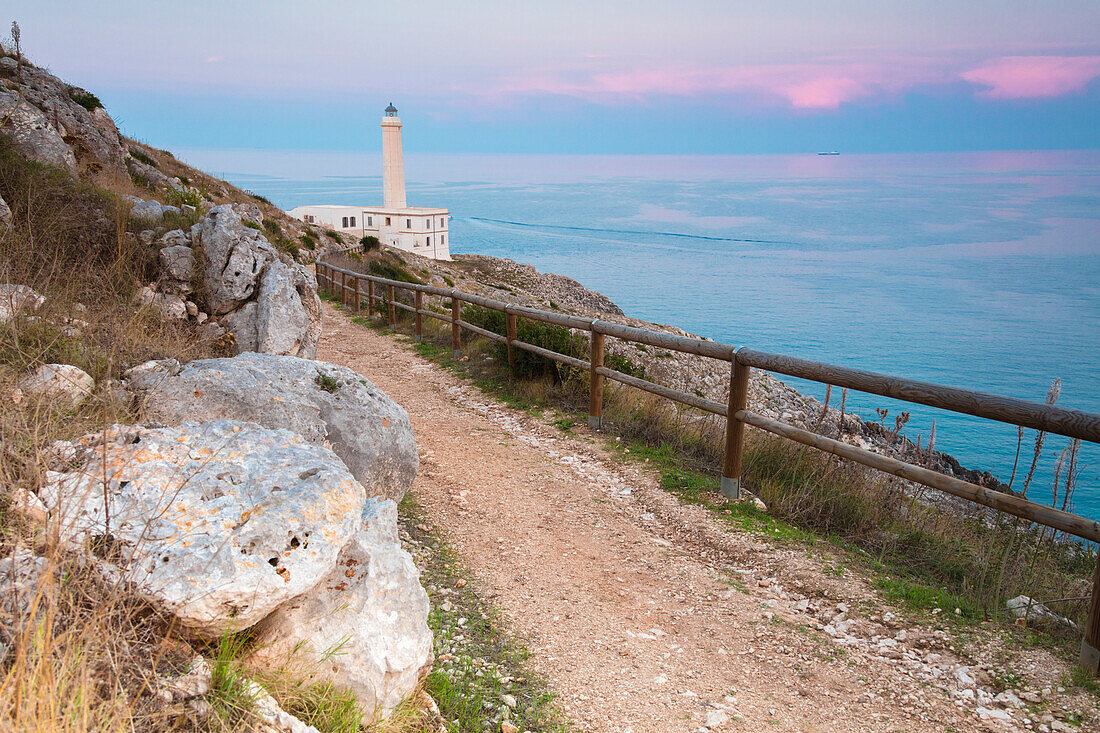 Pink sky on turquoise sea frames the lighthouse at Punta Palascia at sunset Otranto province of Lecce Apulia Italy Europe