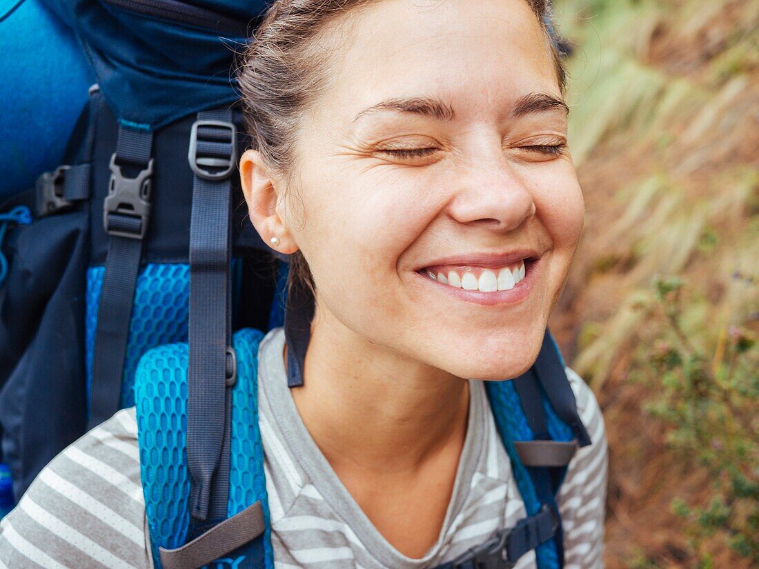 A Smiling Woman With A Backpack Hiking In The Forest