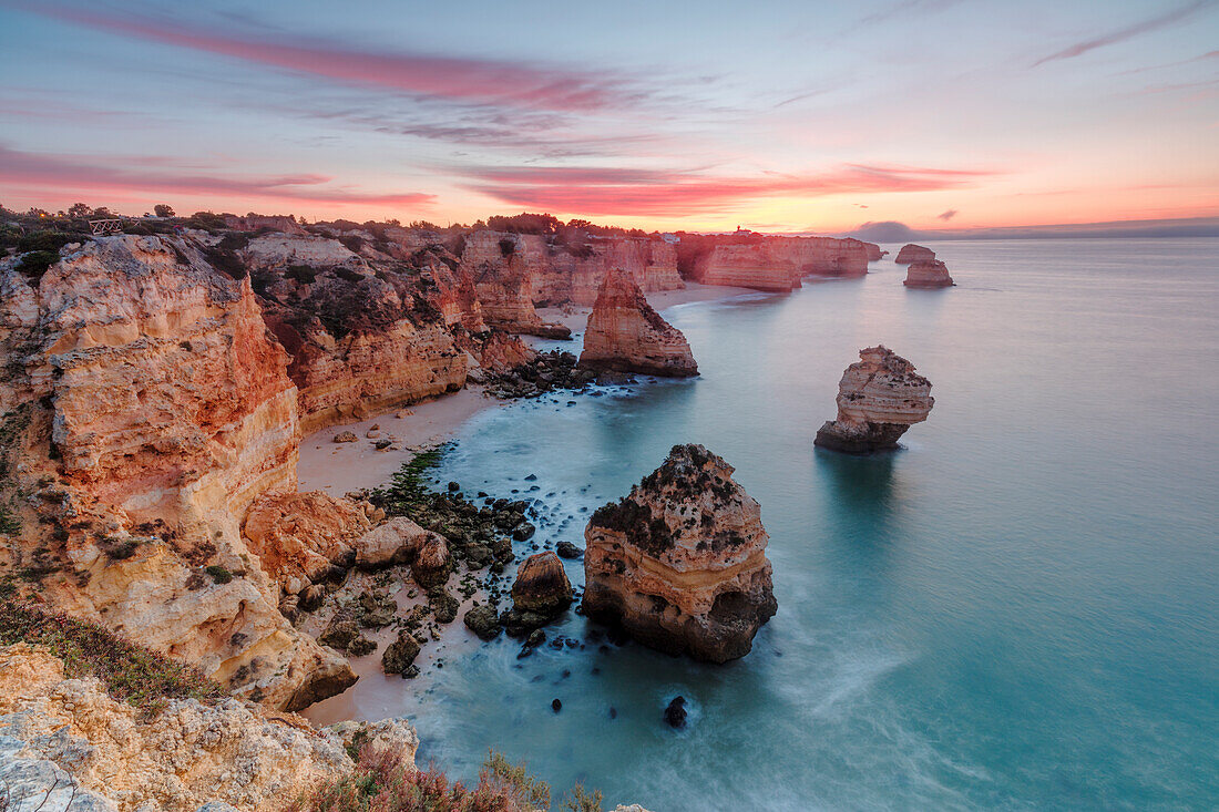 Sunrise on cliffs framed by turquoise water of the ocean, Praia da Marinha, Caramujeira, Lagoa Municipality, Algarve, Portugal, Europe