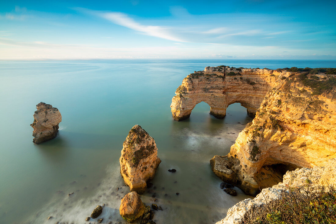 Sunrise on cliffs framed by turquoise water of the ocean, Praia da Marinha, Caramujeira, Lagoa Municipality, Algarve, Portugal, Europe