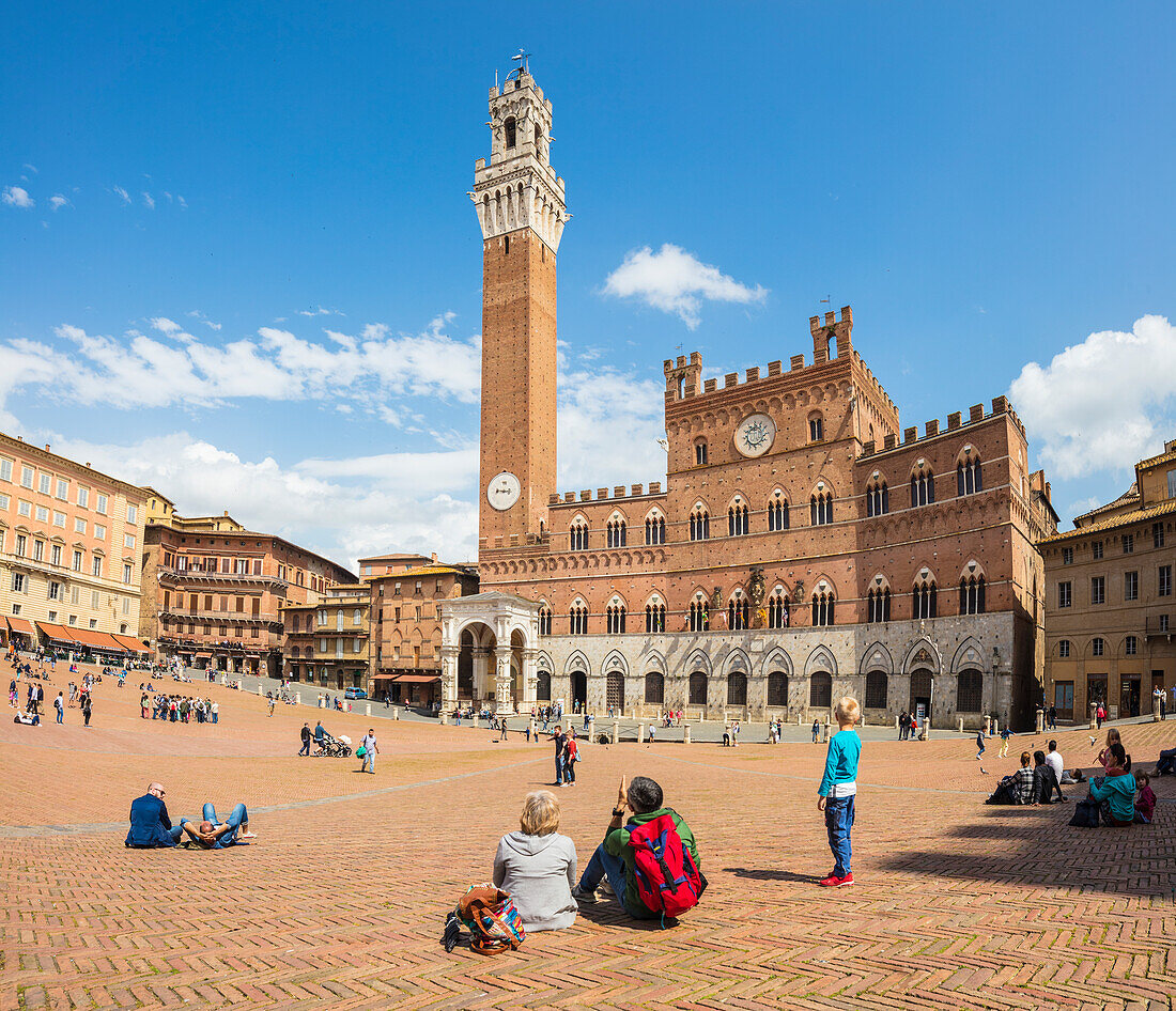 Tourists admire the historical Palazzo Pubblico and its Torre del Mangia, Piazza del Campo, Siena, UNESCO World Heritage Site, Tuscany, Italy, Europe