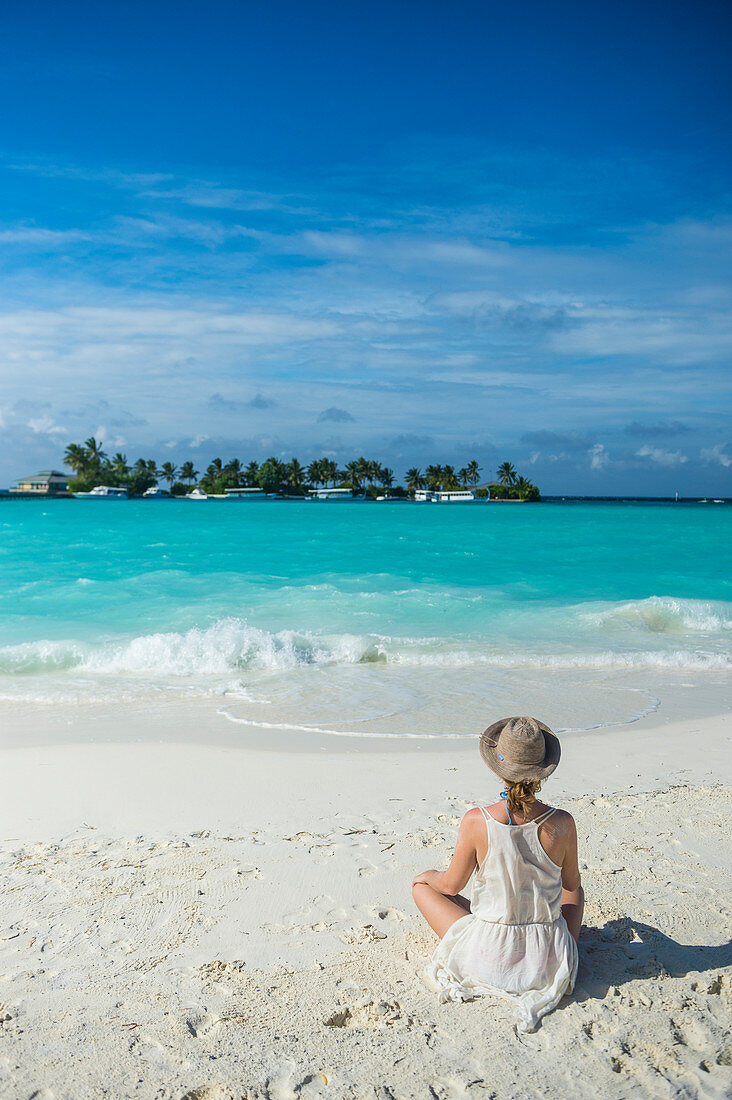 Woman sitting on a white sand beach enjoying the turquoise water, Sun Island Resort, Nalaguraidhoo island, Ari atoll, Maldives, Indian Ocean, Asia