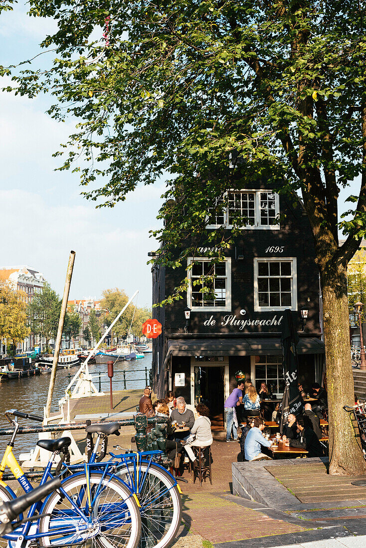 Eines der typischen Bruin Cafes, die eher eine Bar sind, schiefes Café de Sluyswacht, Amsterdam, Niederlande, Europa