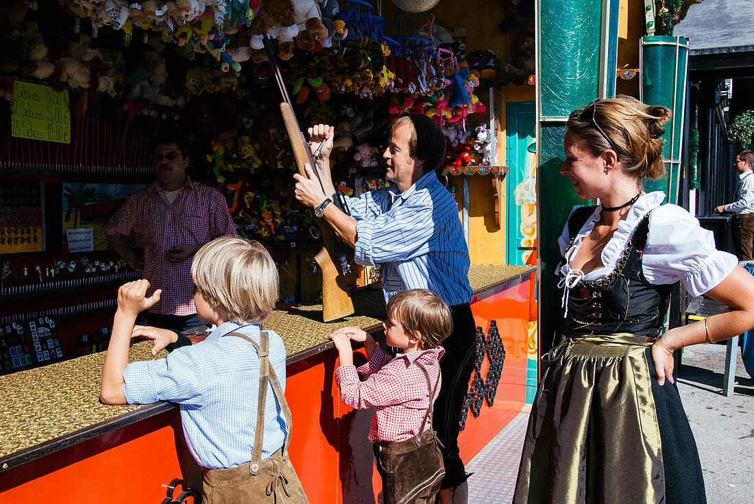 Familie in Tracht am Schießstand im Oktoberfest, München, Bayern, Deutschland