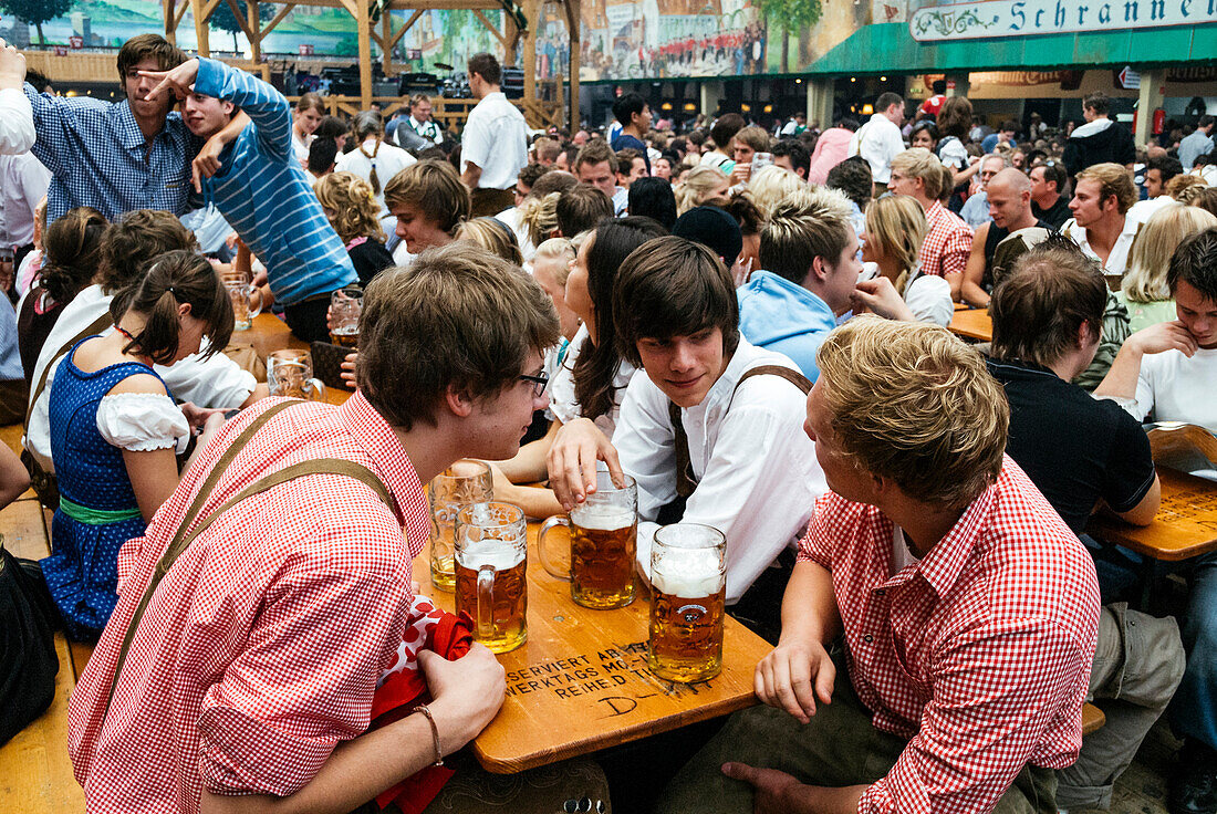 Junge Leute in traditioneller Kleidung mit Bierkrügen, Oktoberfest, München, Deutschland