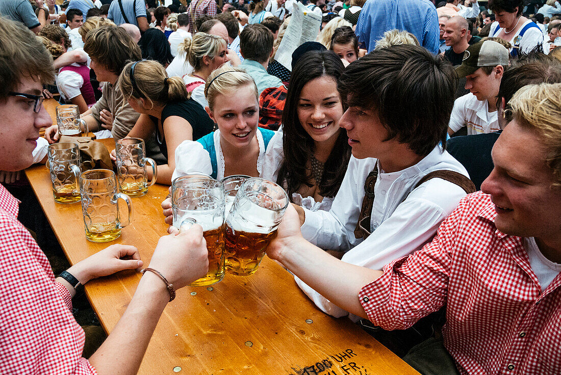 Revelers raise their beer mugs to toast at Oktoberfest, Munich, Bavaria, Germany