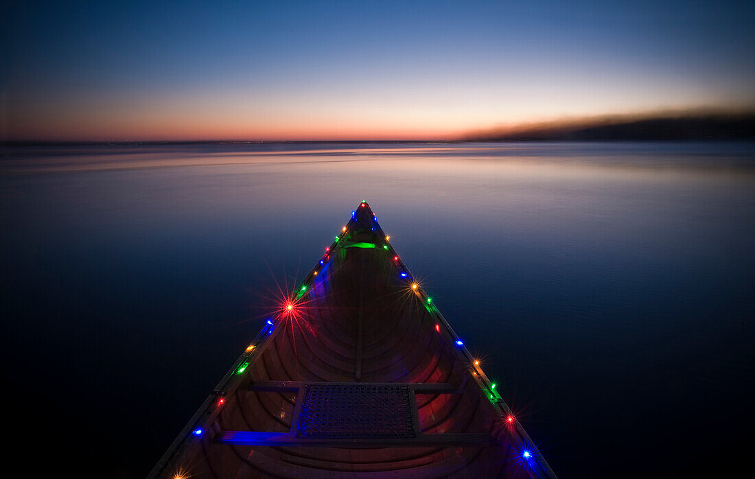 A canoe with two strands of led christmas lights attached to the rails. Shot on Lake Monona in Madison, WI during the month of December.