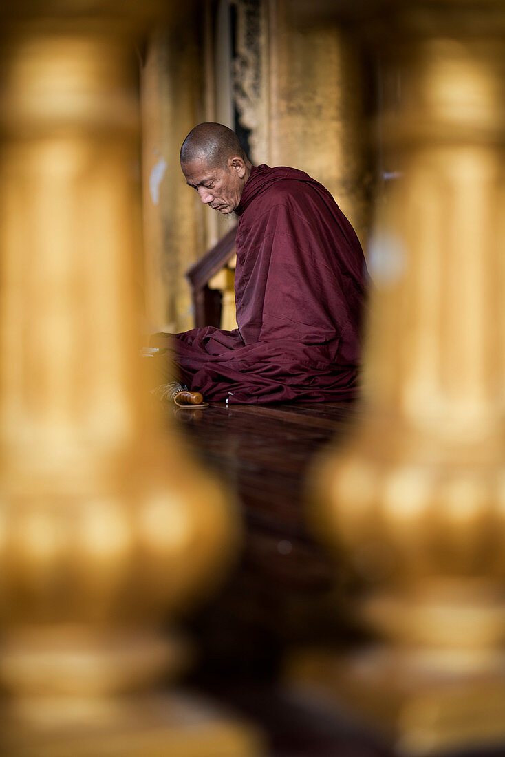 A Buddhist monk prays at the Shwedagon pagoda, Yangon, Myanmar.