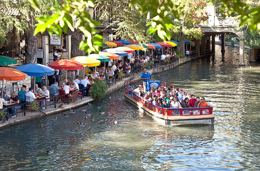 A fully loaded riverboat makes the curve in front of Casa Rio Restaurant on San Antonio's famous Riverwalk.  Once a dismal drainage ditch through the heart of downtown, today's Riverwalk draws thousands of visitors annually.  Portions are lined with eater
