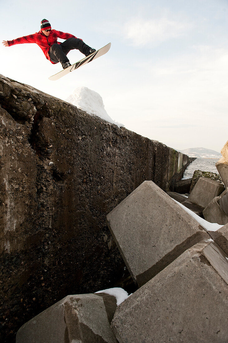 Low angle view of snowboarder jumping on rock