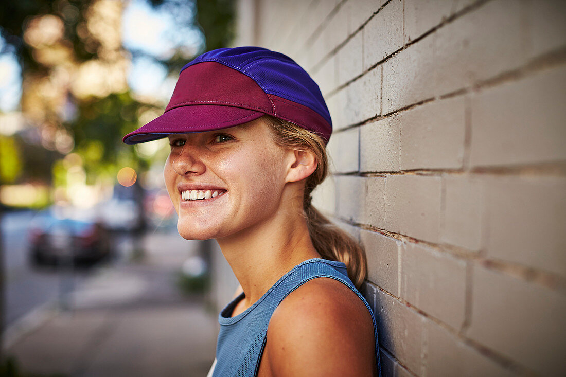 Close-up Of Smiling Female Athlete Leaning On Wall