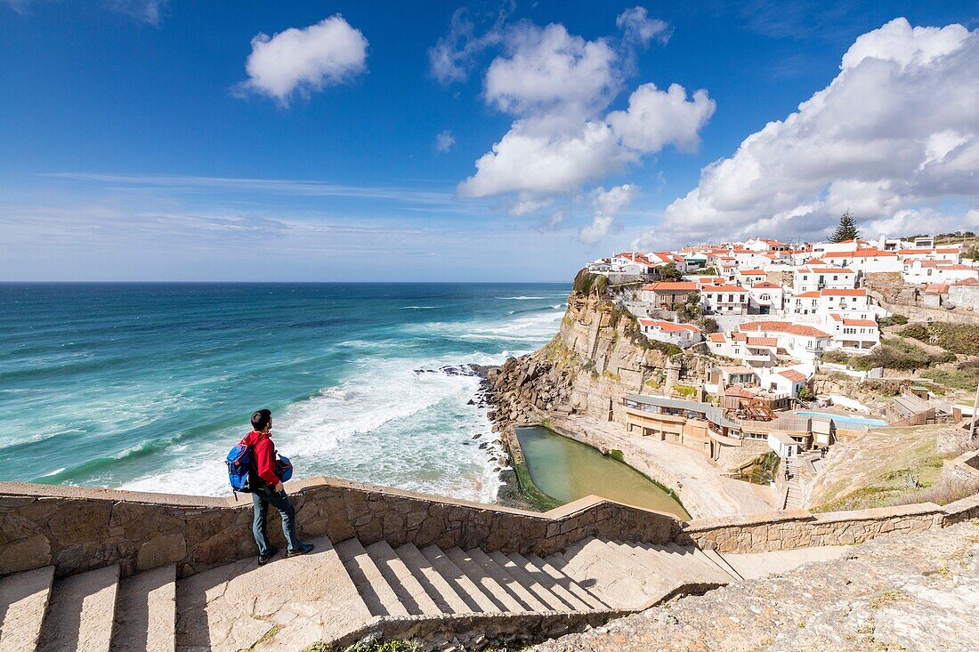 Tourist admires the perched village of Azenhas do Mar surrounded by the blue water of the Atlantic Ocean Sintra Portugal Europe
