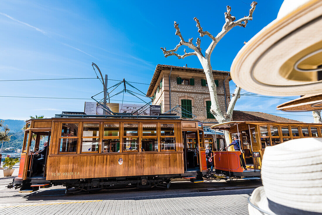 Die berühmte uralte Straßenbahn zwischen Port de Sóller und Sóller passiert einen Laden mit Hüten, Port de Sóller, Mallorca, Spanien