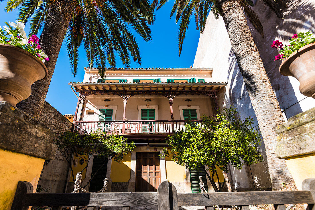 Ein typisches altes Haus mit Veranda eingerahmt von Palmen, Valldemossa, Mallorca, Spanien