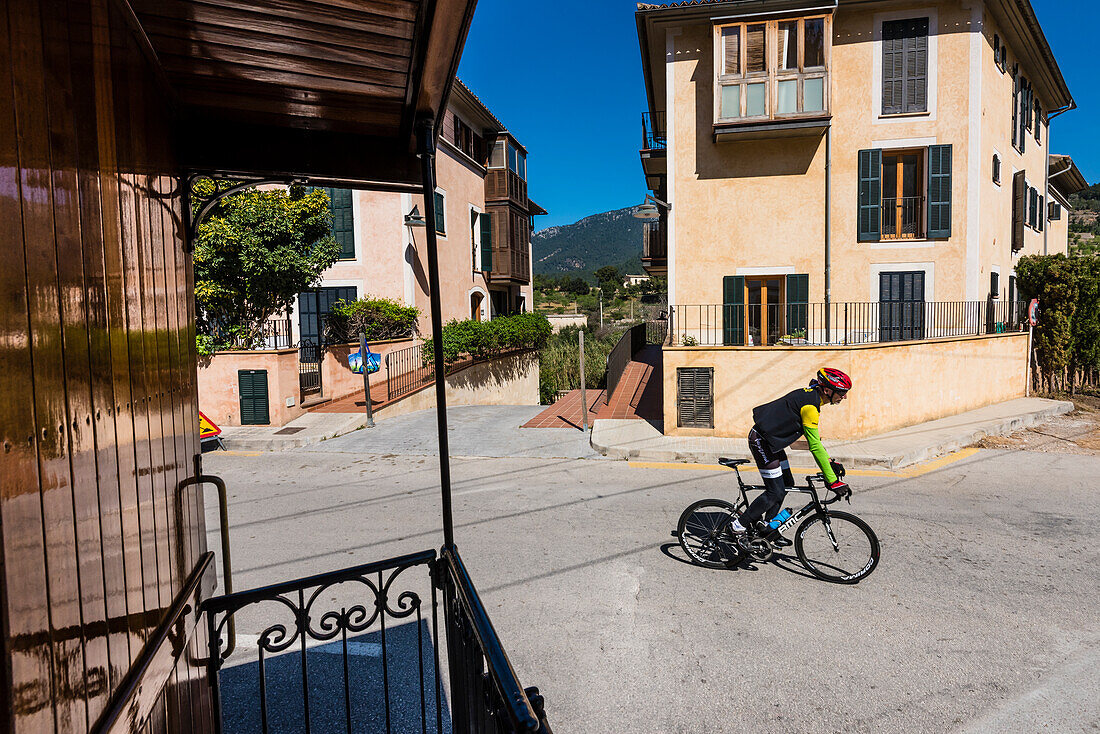 Blick aus dem historischen Zug zwischen Sóller und Palma auf eine Straße mit einem der vielen Radsportler, Bunyola, Mallorca, Spanien