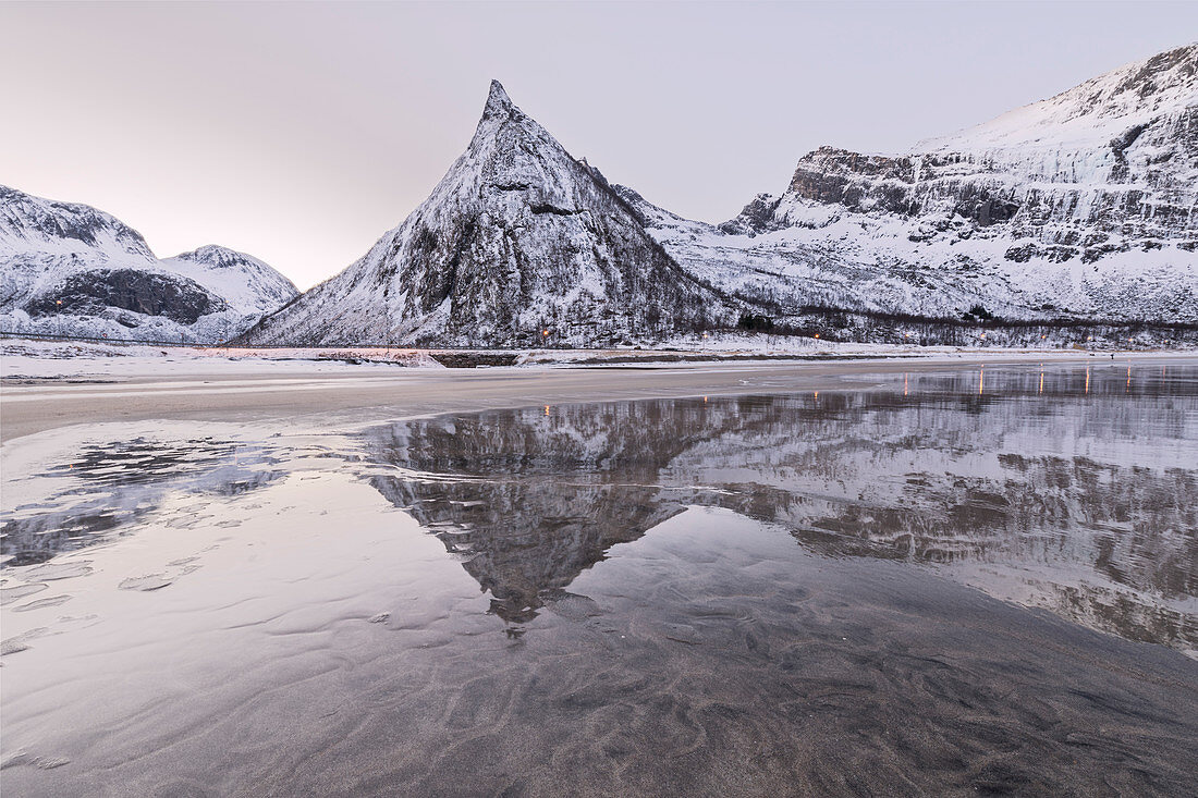 Schneebedeckte Gipfel spiegelt sich im gefrorenen Meer, umgeben von Sandstrand im Morgengrauen, Ersfjord, Senja, Troms, Norwegen, Skandinavien, Europa