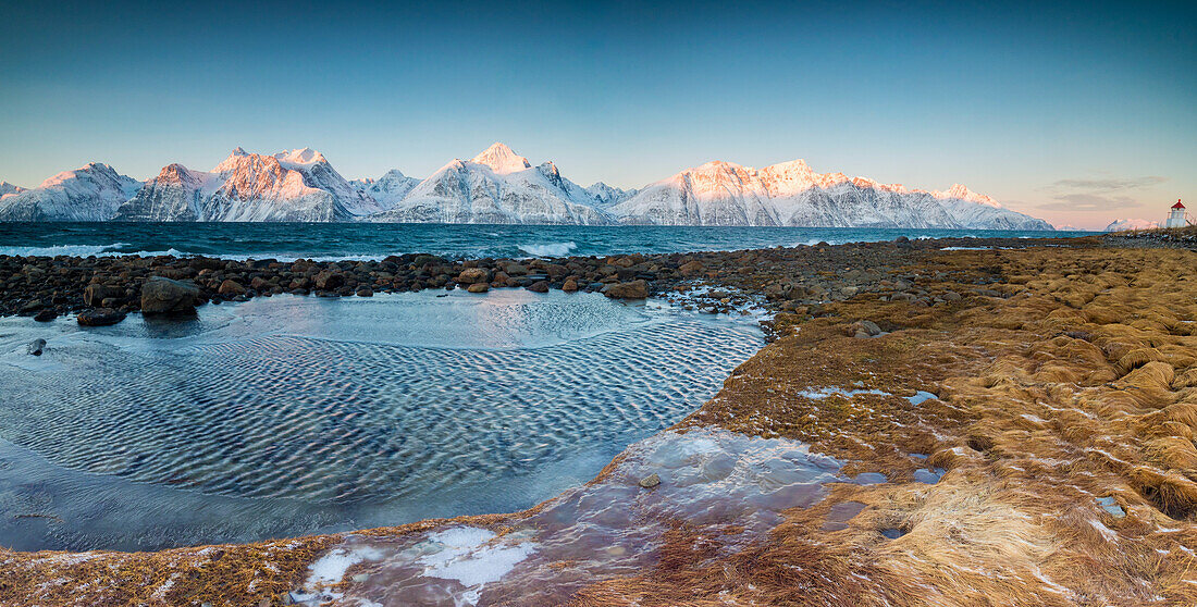 Panorama von gefrorenem Meer und schneebedeckten Gipfeln in der Morgendämmerung umgeben von Felsen mit Eis bedeckt, Djupvik, Lyngen Alpen, Troms, Norwegen, Skandinavien, Europa