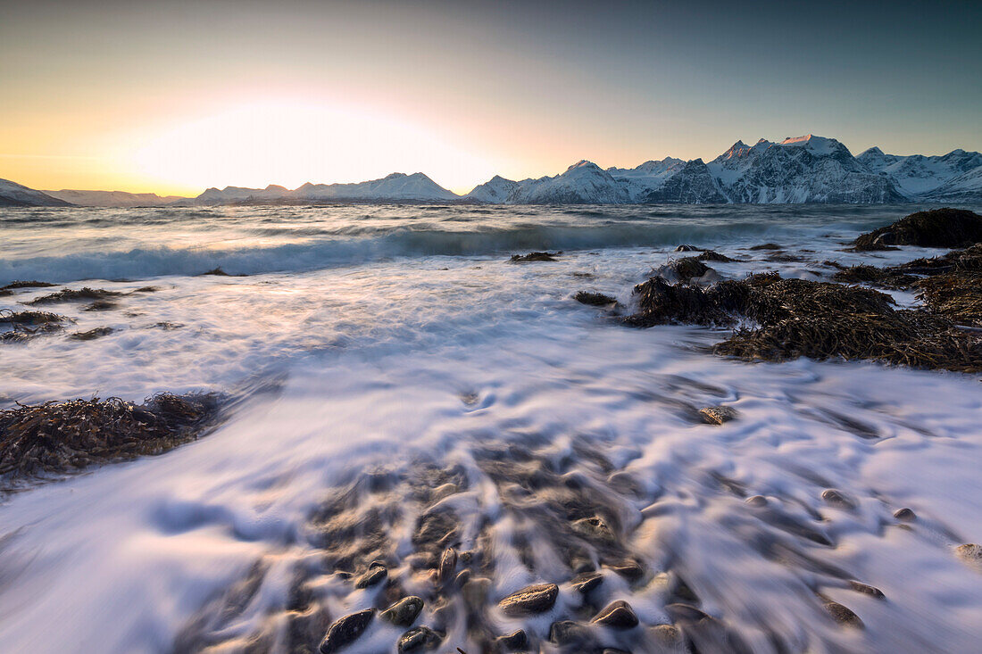 Der Sonnenuntergang Licht reflektiert auf den Wellen der kalten Meer Absturz auf den Felsen, Djupvik, Lyngen Alpen, Troms, Norwegen, Skandinavien, Europa