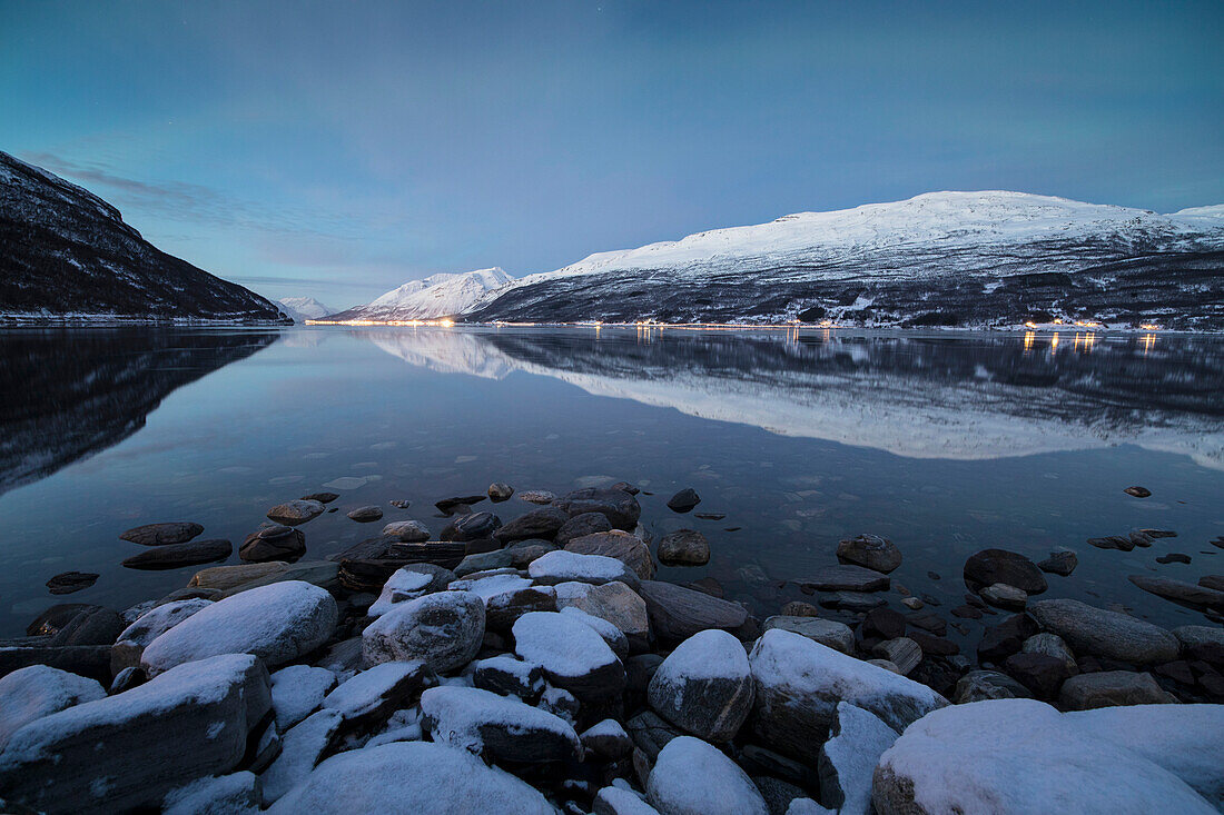 Schneebedeckte Gipfel spiegeln sich im kalten Meer in der Dämmerung, Manndalen, Kafjord, Lyngen Alpen, Troms, Norwegen, Skandinavien, Europa