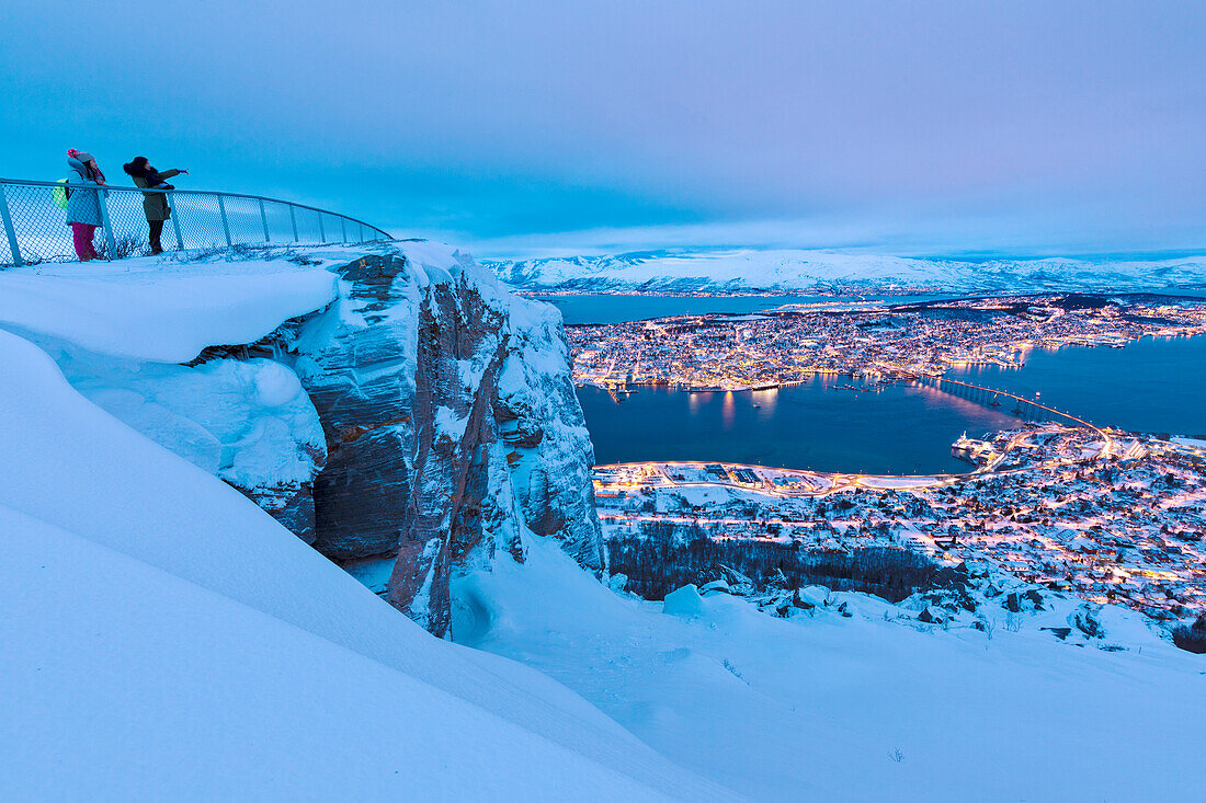 Die Menschen bewundern die Stadt Tromso in der Dämmerung von der Bergspitze, die von der Seilbahn Fjellheisen, Troms, Nordnorwegen, Skandinavien, Europa erreicht wurde