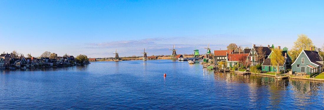 Panorama von Holzhäusern und Windmühlen umrahmt von den blauen Fluss Zaan, Zaanse Schans, Nordholland, Niederlande, Europa