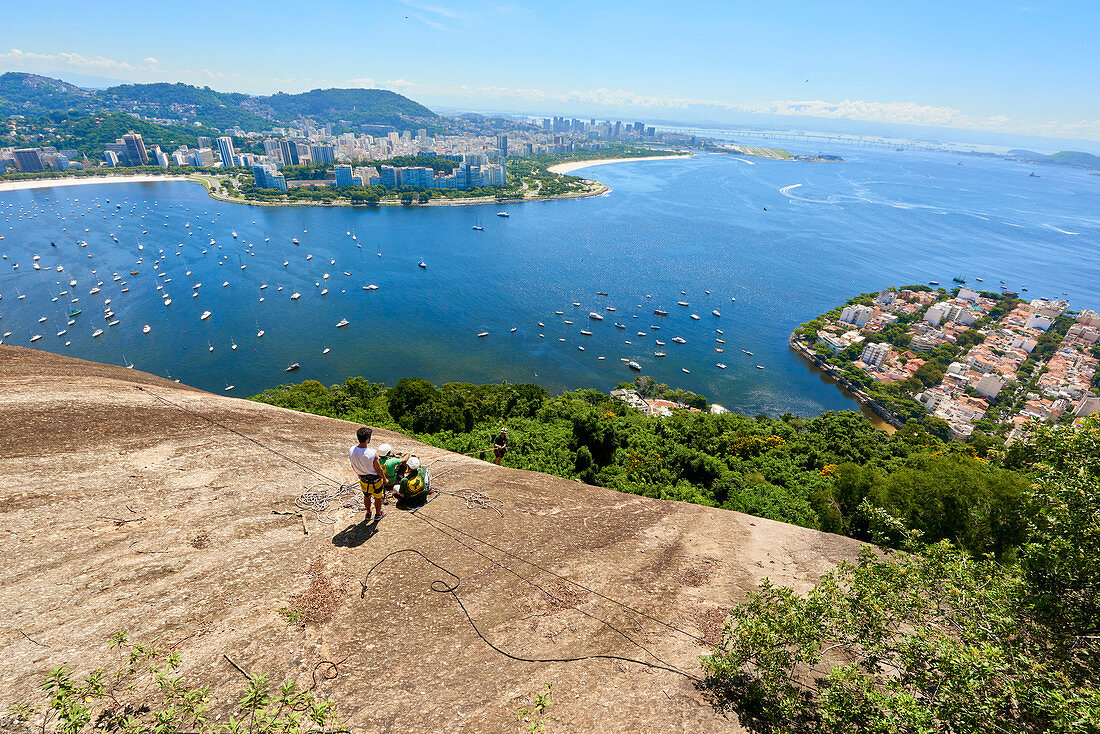 Abseilers in Morro da Urca in Rio de Janeiro with panoramic view in the background, Rio de Janeiro, Brazil, South America