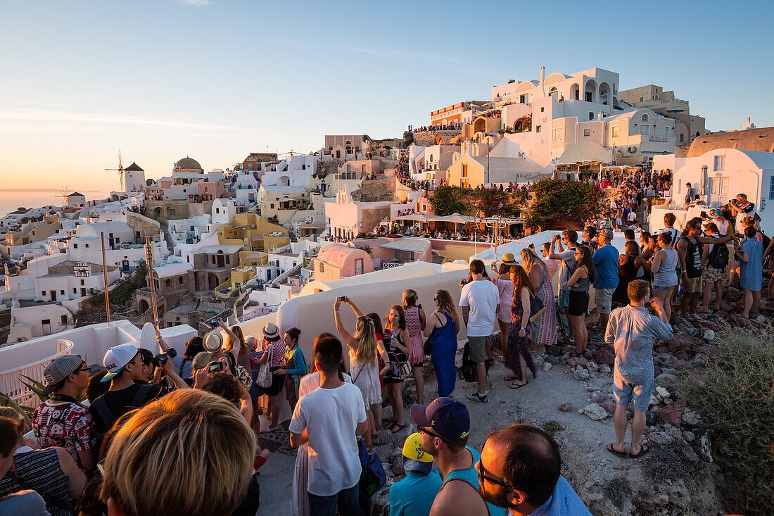People line the town's walls, for the famous Oia sunset on the Greek island of Santorini, Cyclades, Greek Islands, Greece, Europe
