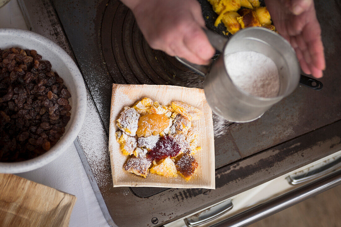 a close up of a cook spinkling icing sugar over the Kaiserschmarrn, a typical south tyrolean food, Bolzano province, South Tyrol, Trentino Alto Adige, Italy, Europe