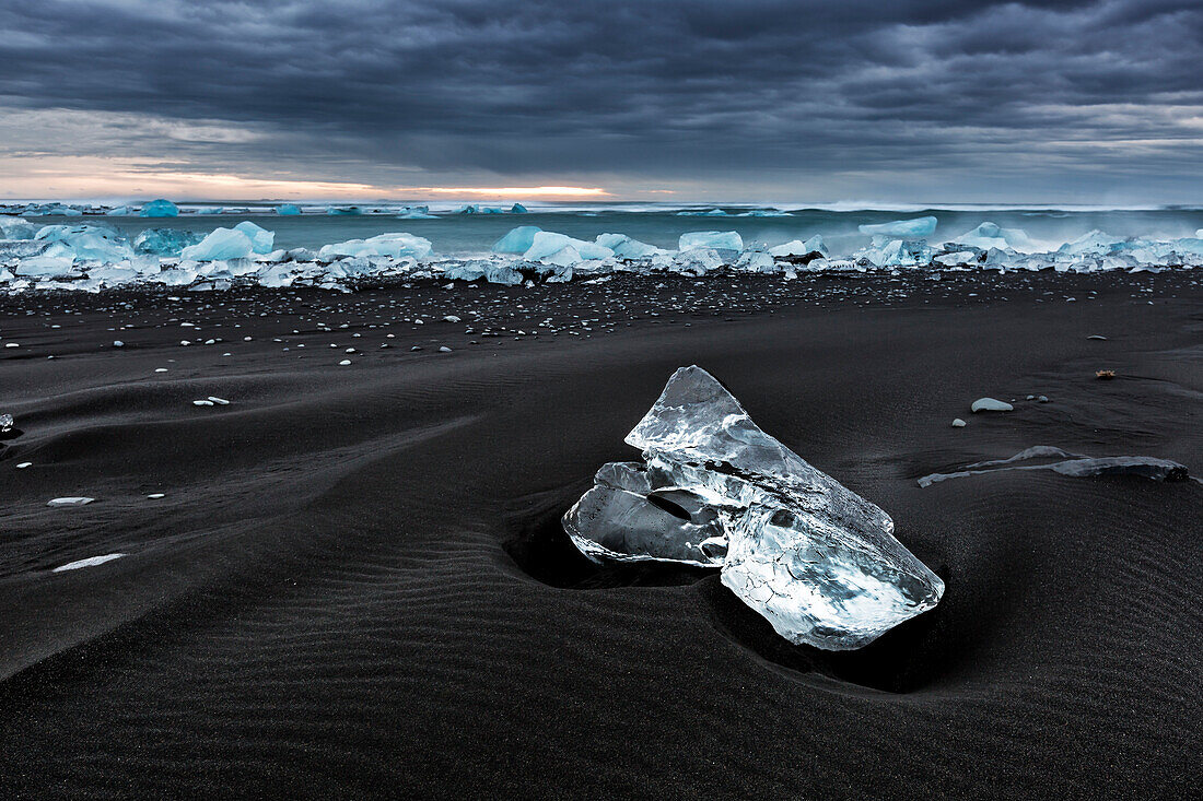 Eine Eisscholle auf dem Jokulsarlon schwarzen Strand, Süd-Island