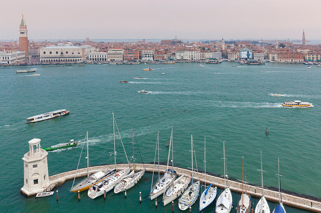 Europe, Italy, Veneto, island of San Giorgio Maggiore, One of the headlights of the dock and some moored boats, on the background St, Mark and the historic center of Venice