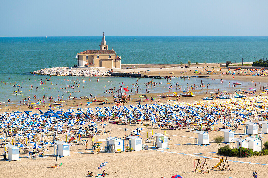 Sun umbrellas on the sand beach overlooking the Sanctuary of Madonna dell'Angelo in Caorle Venice province Veneto Italy Europe